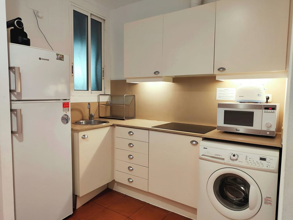 The refrigerator is conveniently located next to the sink, and the washing machine is tucked away in a corner.