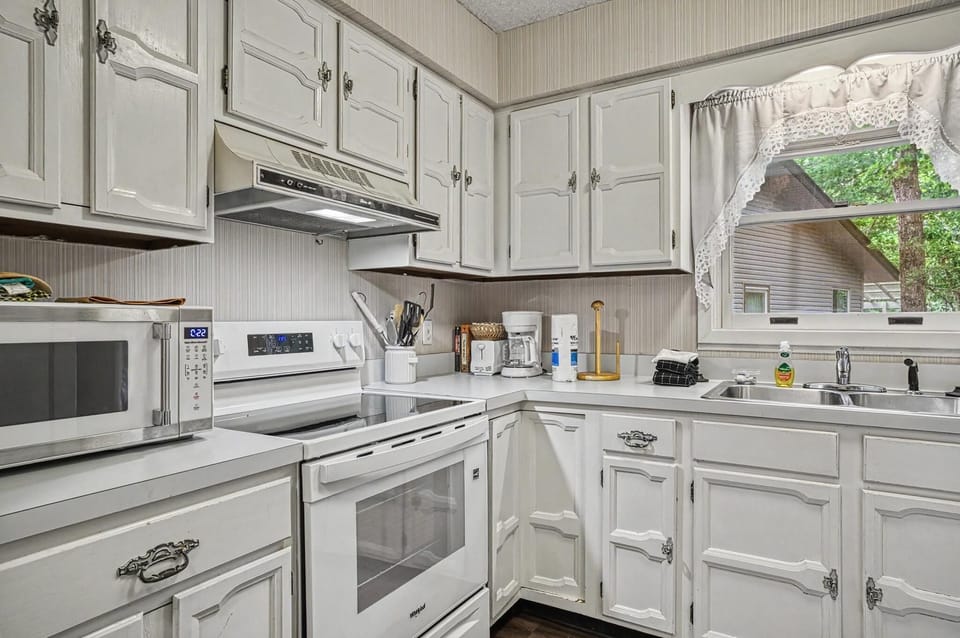 Step into a bright, fully equipped kitchen where you'll find everything you need to whip up meals during your stay—from the microwave and stove to ample counter space and charming cabinet storage.