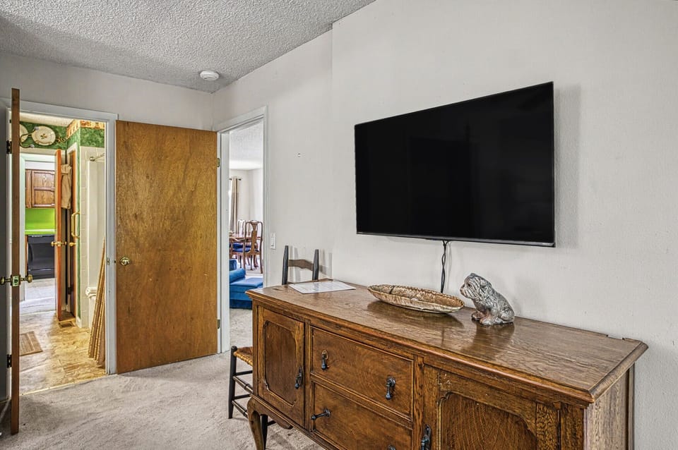 Settle into your cozy bedroom retreat, featuring a wall-mounted flat-screen TV and charming vintage-style furniture that adds character to your stay.