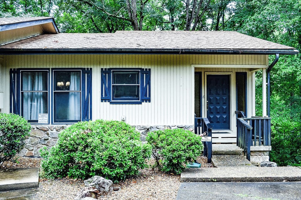A cozy cottage nestled among lush greenery, offering a peaceful retreat surrounded by mature trees and landscaped gardens.