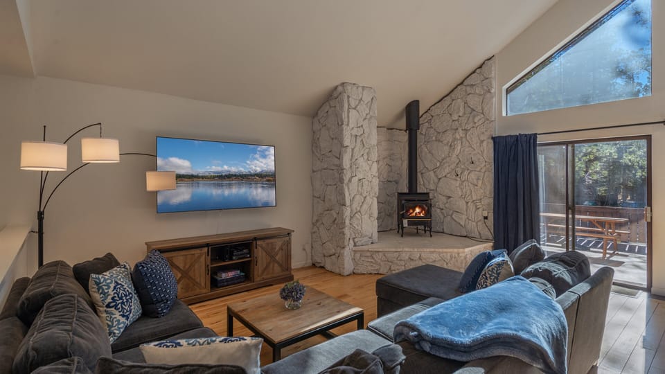 Living room with gas stove and 70 inch smart tv with cable.