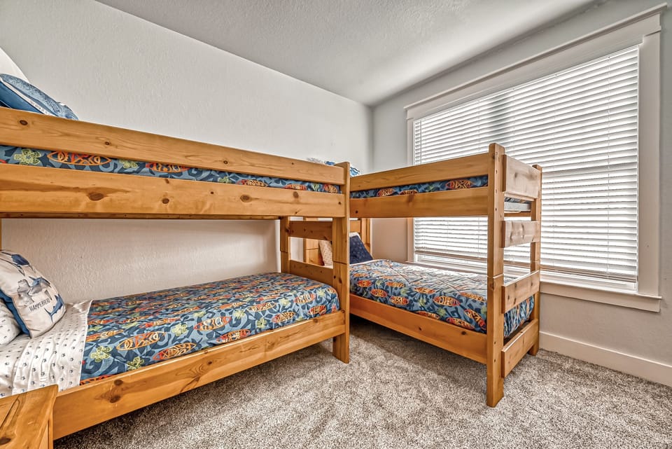 Bunk room features 4 twin beds, chest of drawers, closet, and TV with smart box.