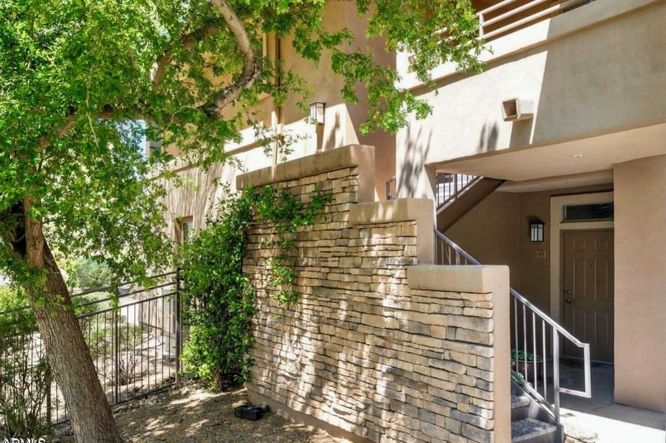 stairs to front door next to grassy area and gas grills