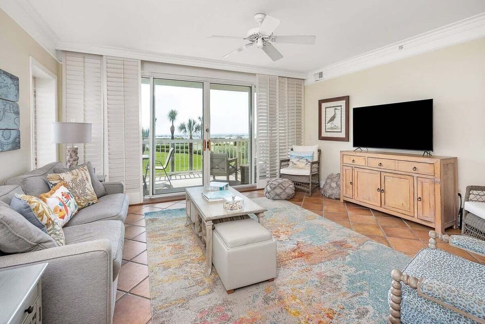 St. Simons Grand #102 living room with TV, sofa, side chairs, and patio access