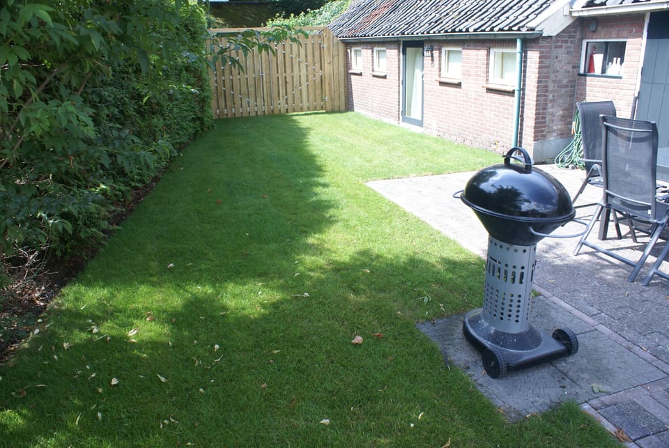 The garden beside the farmhouse including tables, chairs, trampoline and BBQs