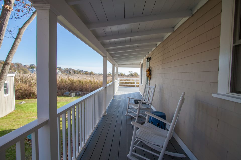 Shaded side porch with rocking chairs and entrance to the living room.