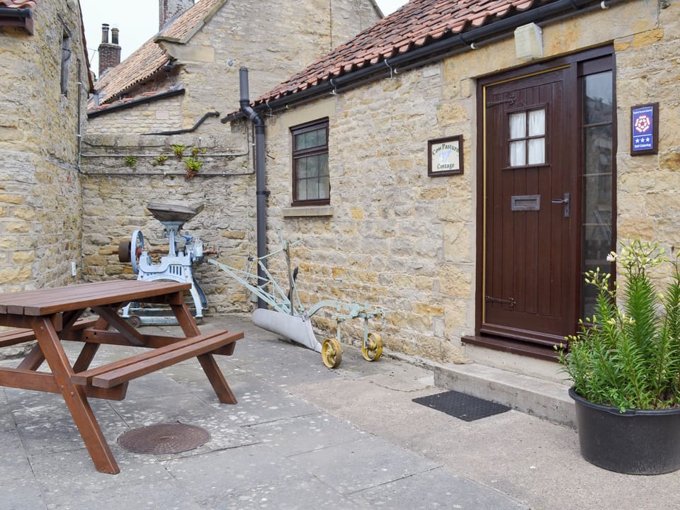 Paved patio with outdoor furniture at entrance | Cow Pasture Cottage - Studley House Farm Cottages, Ebberston, near Scarborough