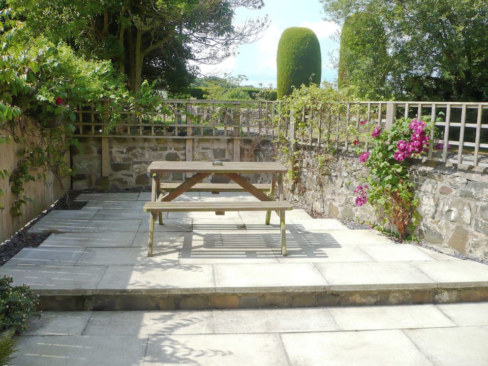 Tranquil patio garden with seating area | Larch Cottage, Dunstan, near Alnwick