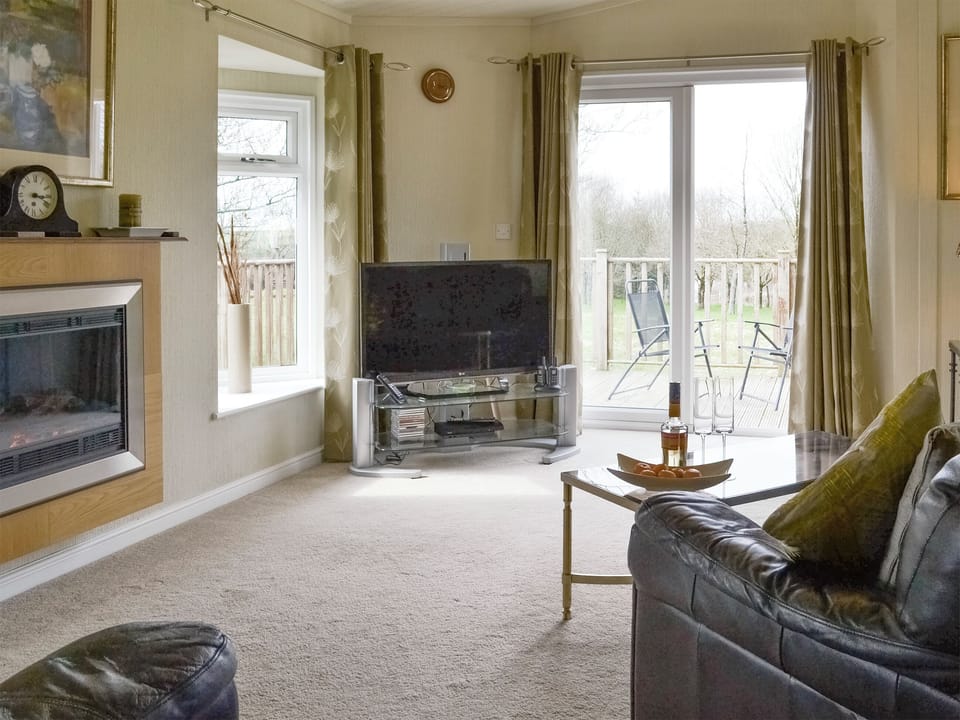 Spacious living area with patio door to decked area | Willow - Thornbury Holiday Park, Woodacott, near Holsworthy