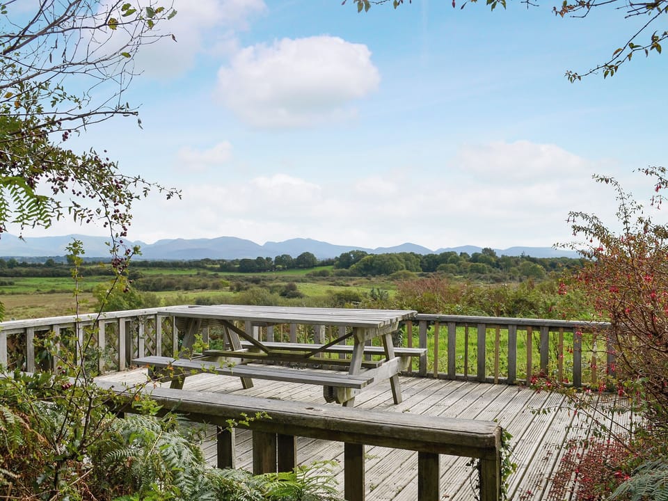 Lovely decked area, a perfect spot to admire the far-reaching views across to the mountains of Snowdonia | Pant Y Mel, Llanbedrgoch, near Benllech