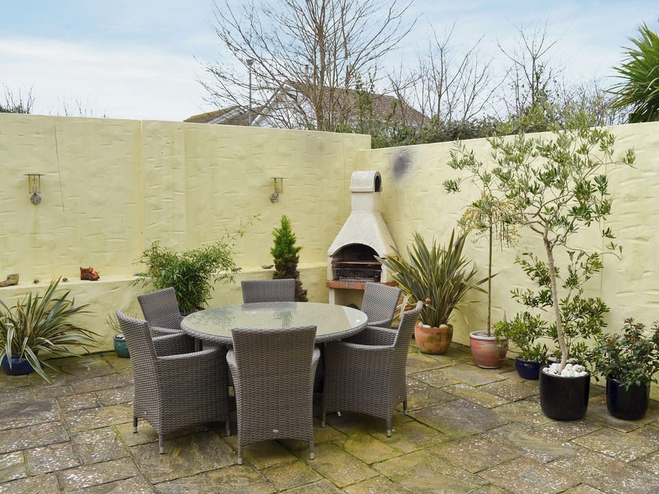 Enclosed paved patio with outdoor furniture and a built-in BBQ | The Old Butchers, Crantock, near Newquay