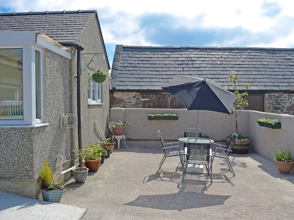 Pretty courtyard with garden furniture and BBQ | Ty Main Cottage, Newborough, near Llangefni
