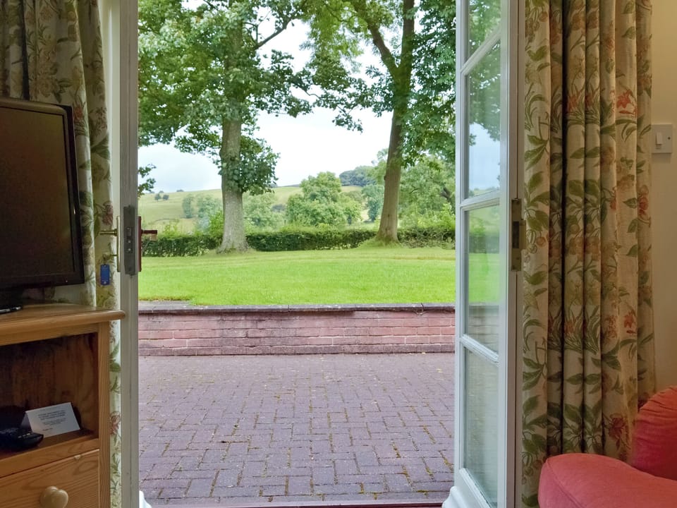 View through French doors from living room to patio and garden | Garden Farm Cottage, Ilam, near Ashbourne