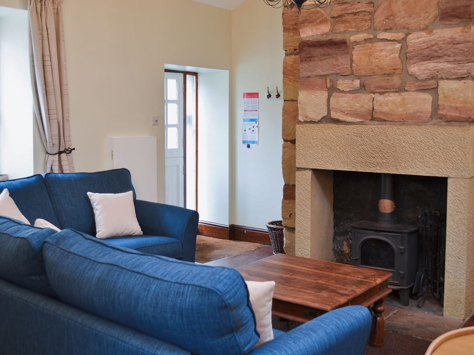 Living room area with a cosy woodburner | The Coracle, Seahouses