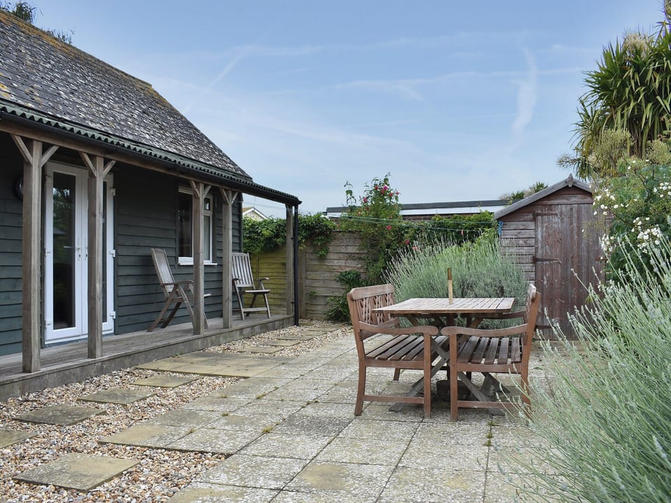 Paved rear garden with table and chairs | Cockle Cottage, Elmer, near Middleton on Sea