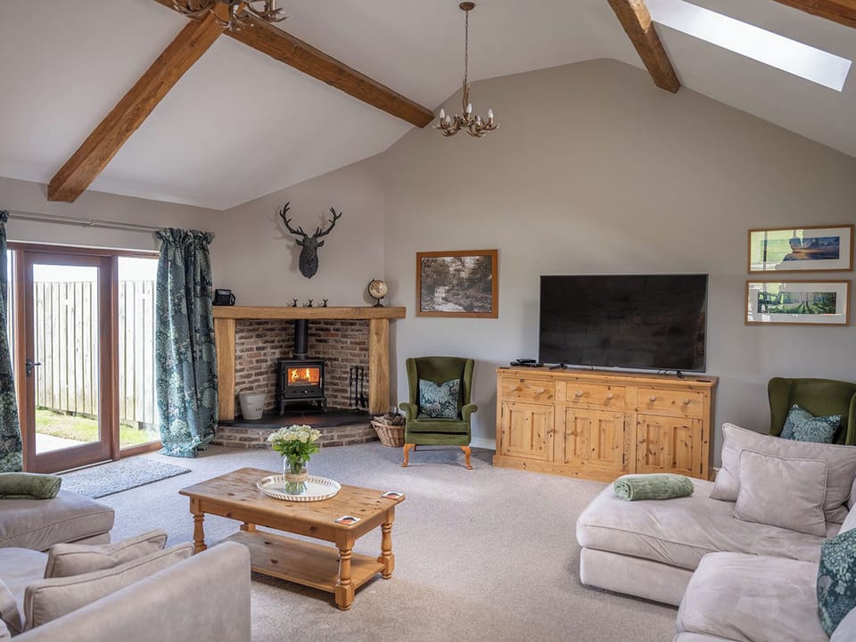 Spacious lounge with vaulted ceiling and beams. Sea views and patio door to the garden area. | Mortar Barn, Sneatonthorpe, near Whitby