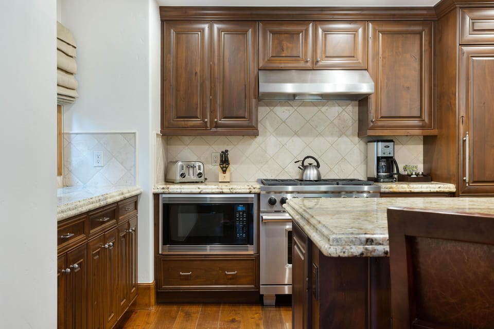 Dark wood cabinets and granite countertops surround stainless steel appliances in the kitchen.