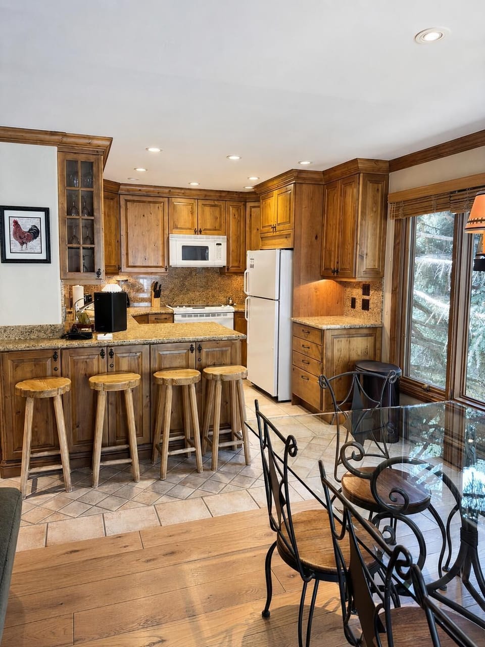 Rustic kitchen features knotty wood cabinets, granite countertops, and four log-style stools along the breakfast bar.