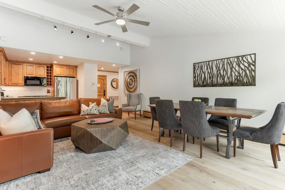 Open living and dining area with leather sectional, geometric wood coffee table, and a wood dining table with six chairs.