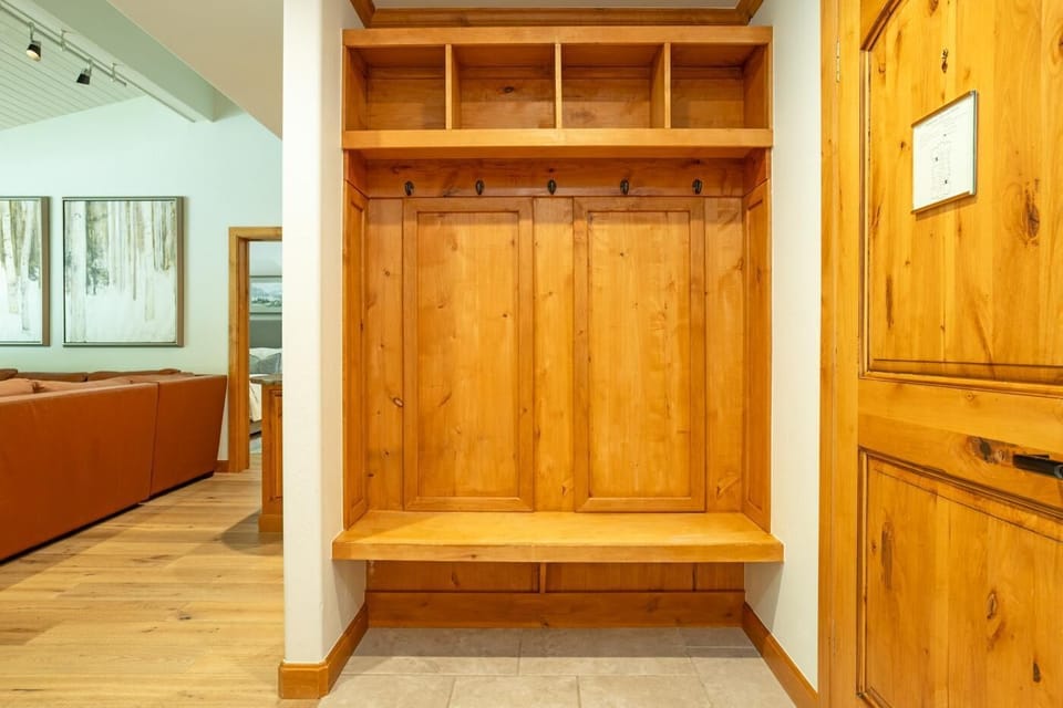 Built-in pine wood cubbies with black hooks and bench seating in the entryway, adjacent to the living area.