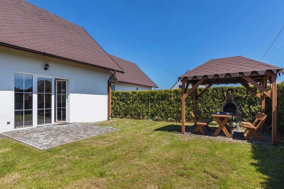 Another view of the wooden gazebo, showing the seating area underneath and its placement within the well-kept garden, creating a perfect outdoor retreat.