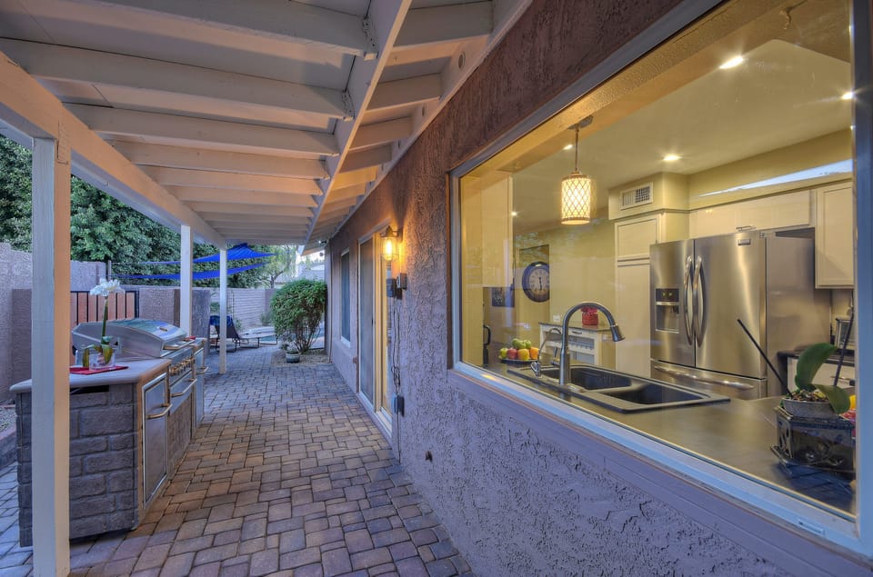 Covered stone walkway with built-in barbecue connects the front and back of home.