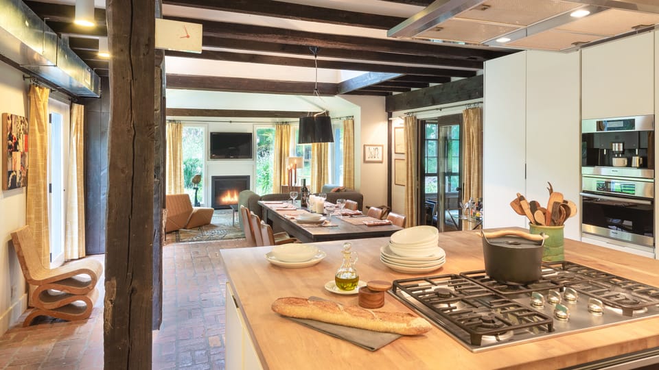 Enter the open-style great room with original posts, beams, and brick floor