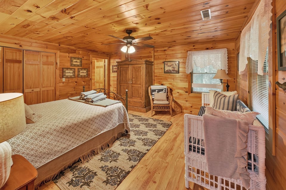 Rustic bedroom with cozy wood paneling and a comfortable seating area.