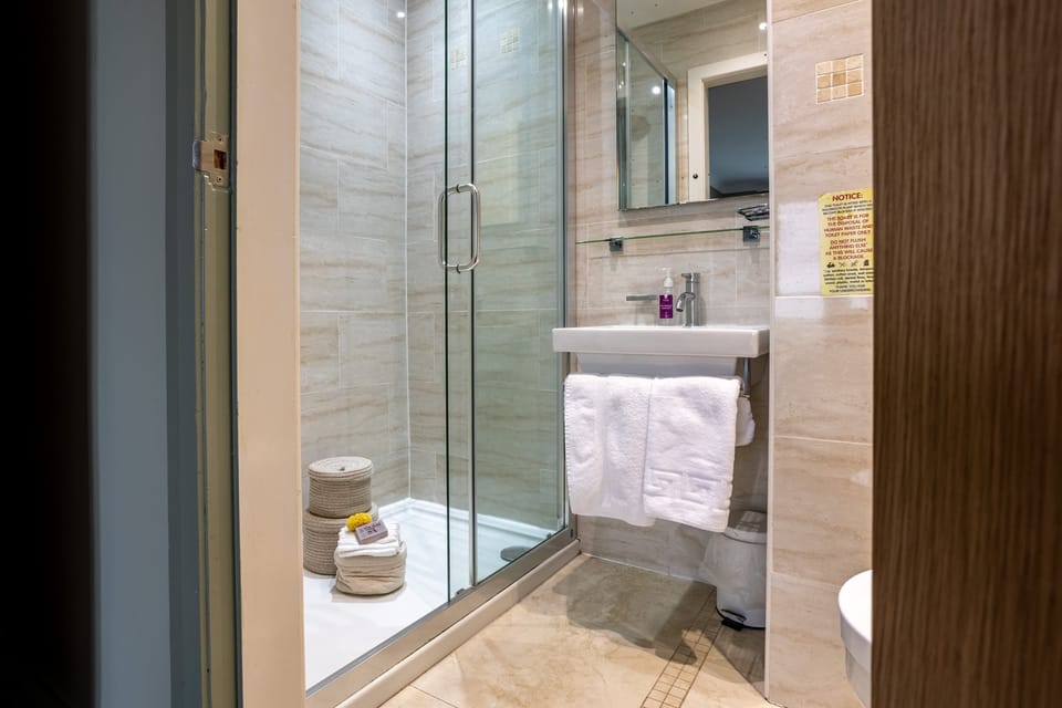 Contemporary bathroom with walk-in shower, dark wood vanity and glass screen, four-bedroom pet-friendly holiday home sleeping eight in Rhosneigr, Anglesey