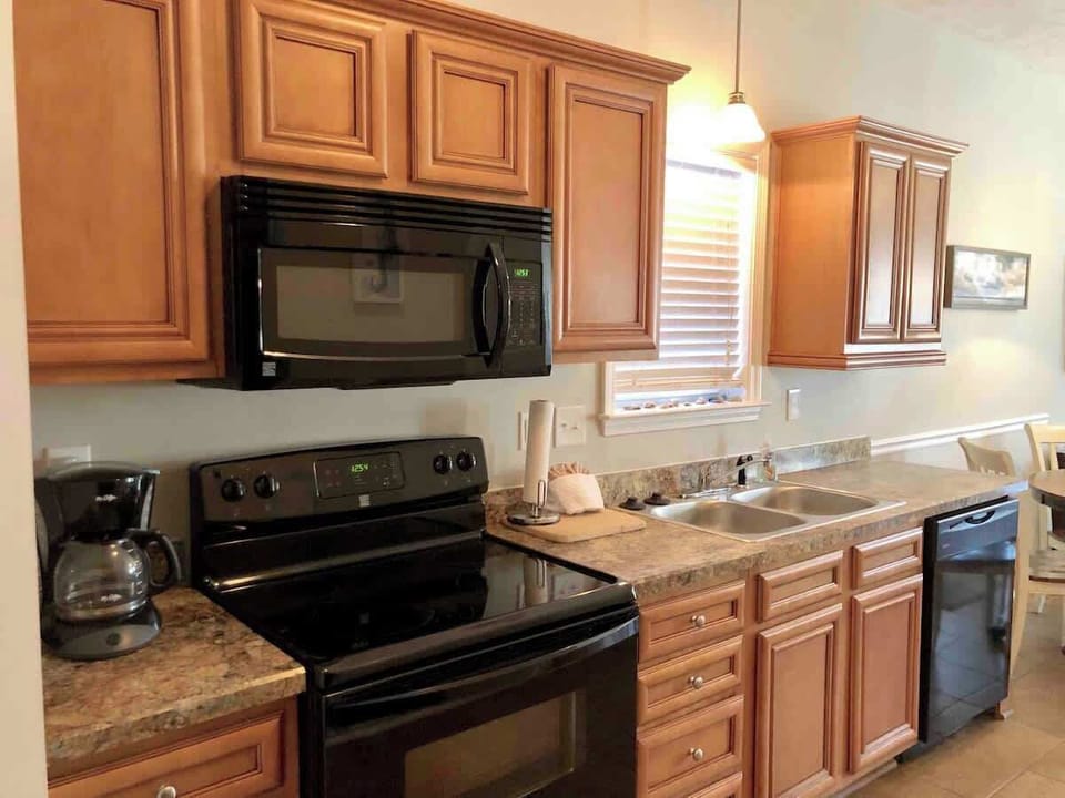 Fully equipped kitchen with stove, oven, fridge, coffee pot, and microwave. 
