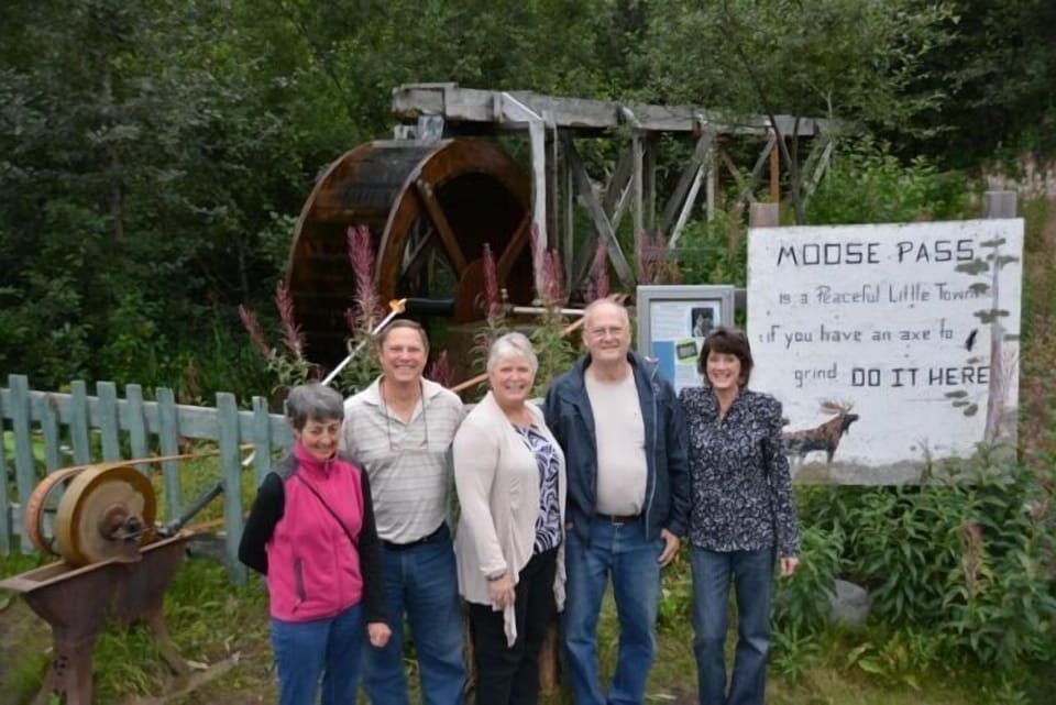 Summer hosts in front of the Moose Pass water wheel.