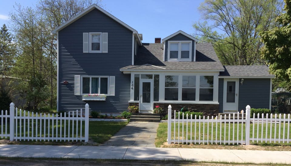 The front of the house with new sidewalk and decorative  fence 
