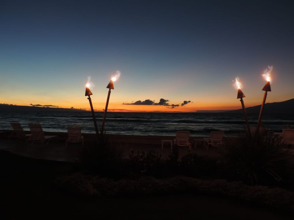 Tiki torches at sunset add to the Hawaiian ambiance