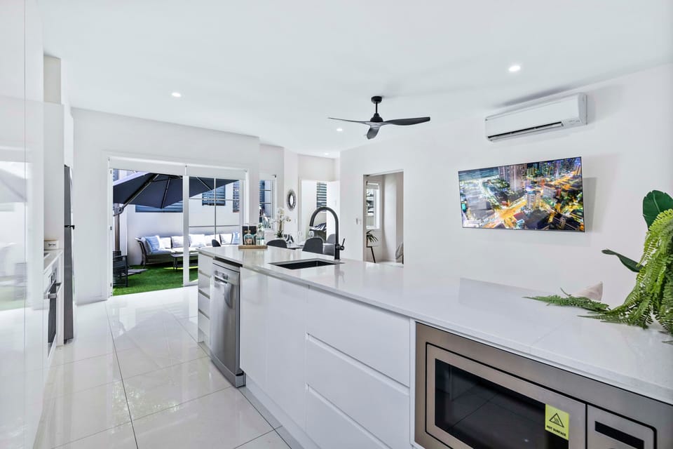 Bright open-plan kitchen anchors living, 65” Smart TV and courtyard nearby.