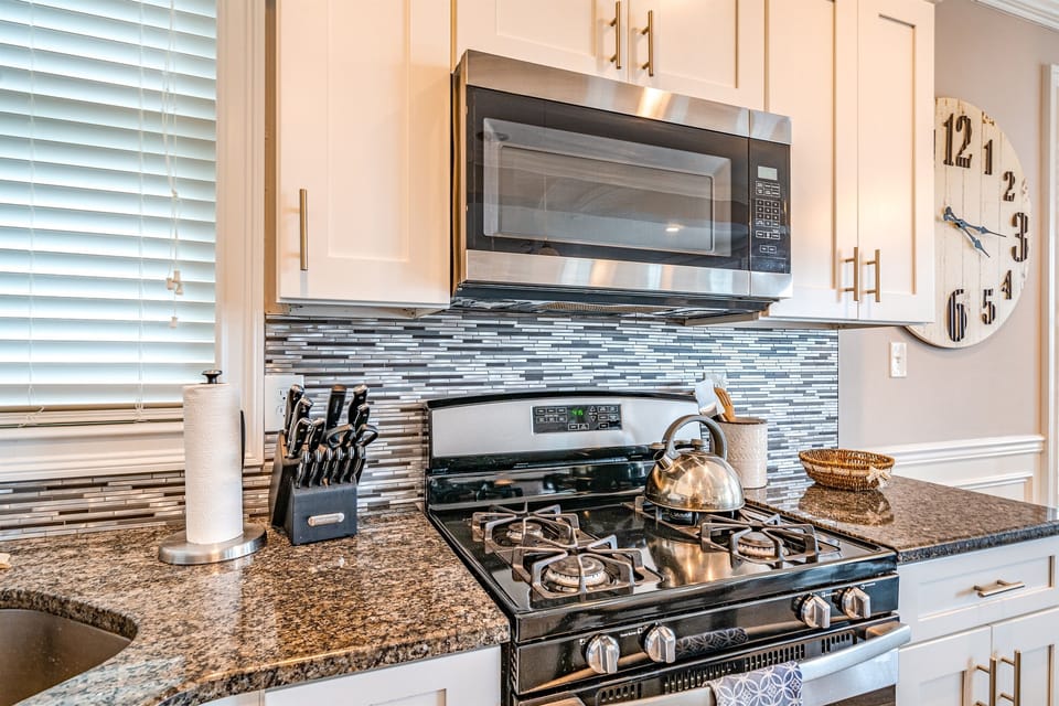 Modern kitchen with stainless steel gas range and granite counters