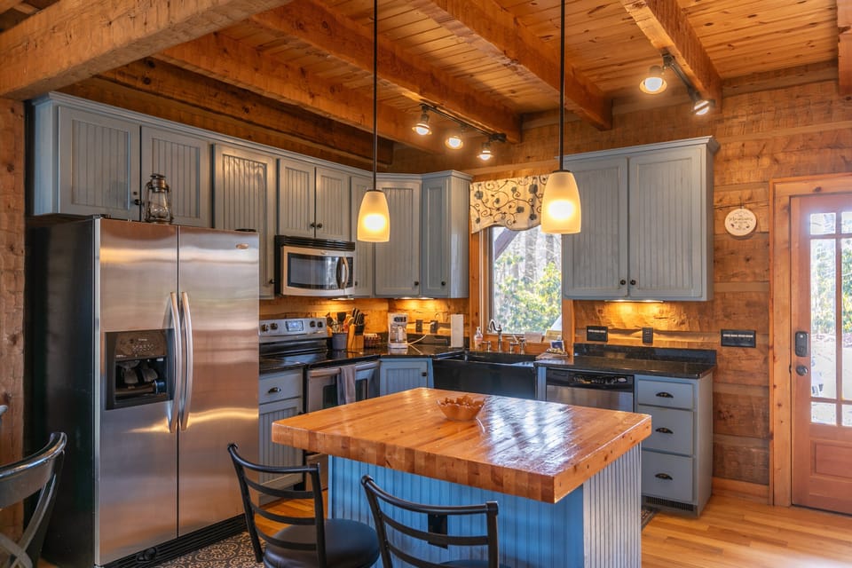 A warm, well-equipped kitchen at Walk In The Clouds, where timber beams and a butcher block island set the tone for mountain mornings.
