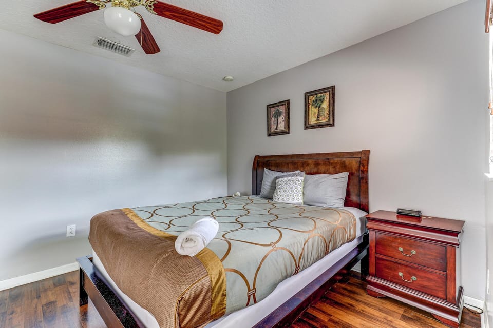 King bedroom with dark wood sleigh bed, patterned bedding, matching nightstand, and hardwood floors.