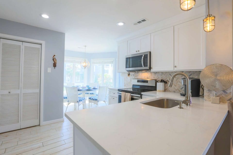 The kitchen features white cabinets, stainless steel appliances and a tiled backsplash.