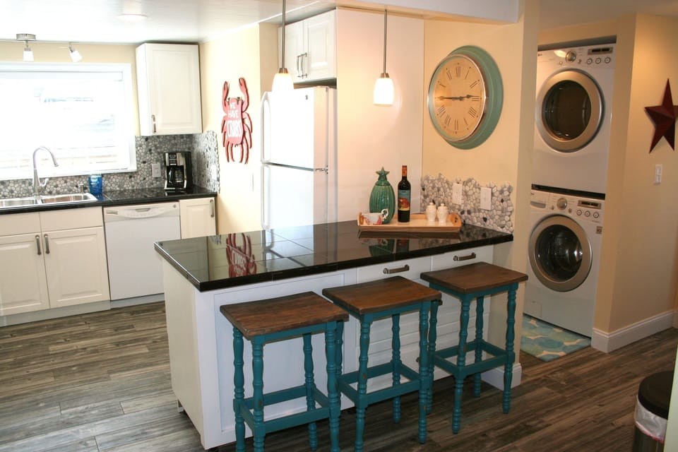 Full kitchen with granite counters and island seating for three.