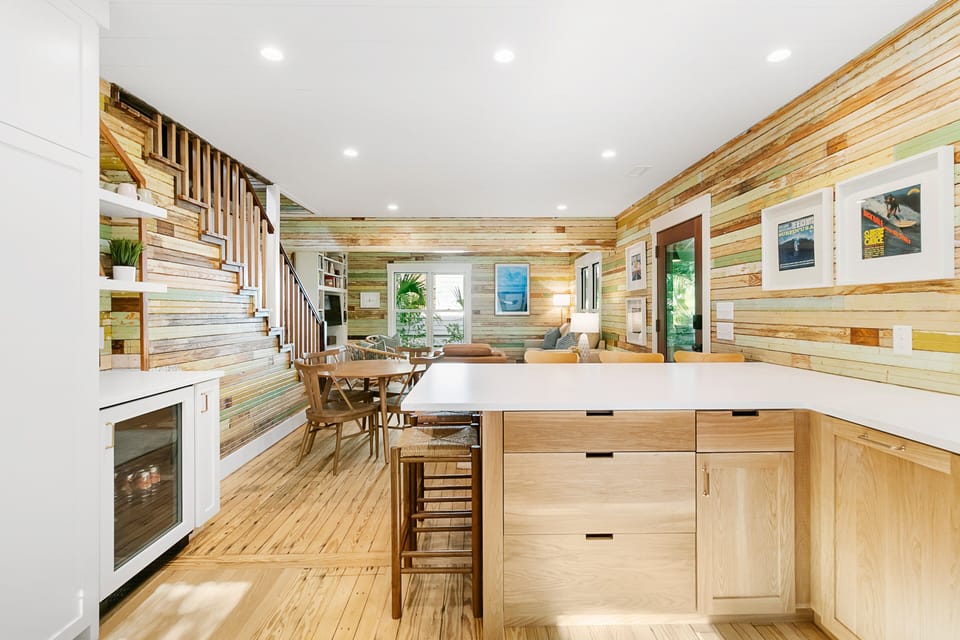 The kitchen flows seamlessly into a dining area with a round table and a living room with built-in bookshelves and a Smart TV.