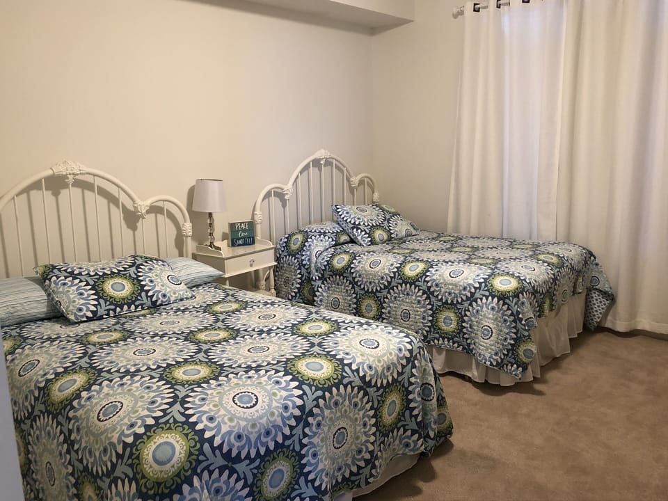 The large  guest bedroom with two full size beds. There is a flat screen tv.