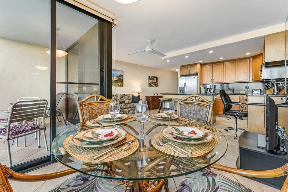 Dining area with round rattan and glass table and 4 matching chairs.
