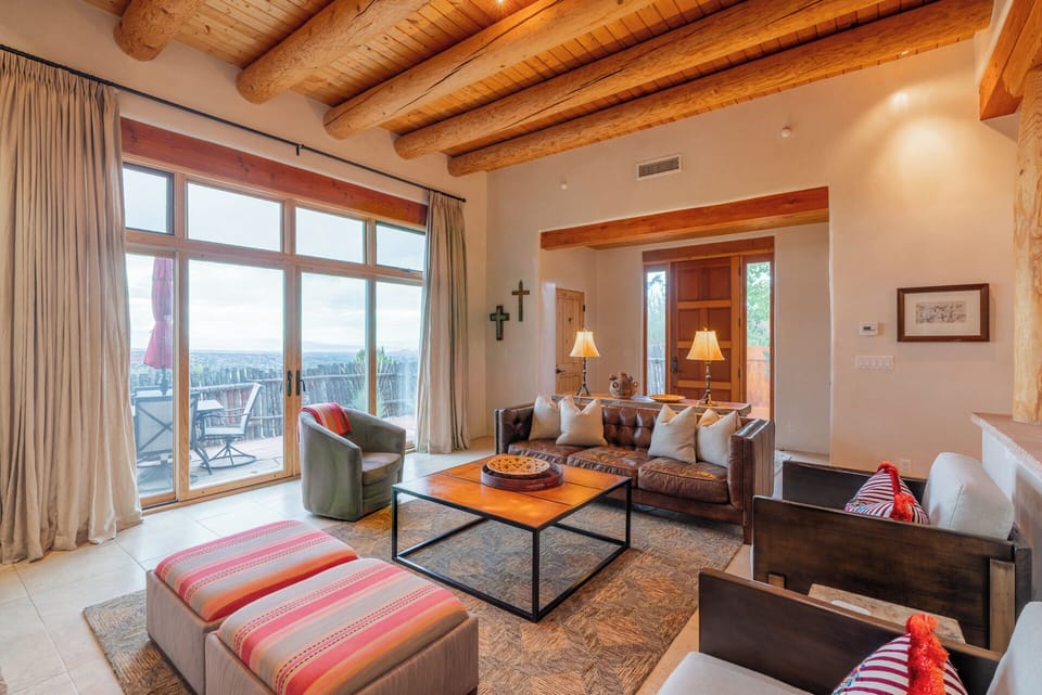 Relax in your open, light-filled living room where Southwestern charm meets comfort. Exposed wood beam ceilings, rich leather seating, and mountain views through expansive windows create your perfect retreat space.