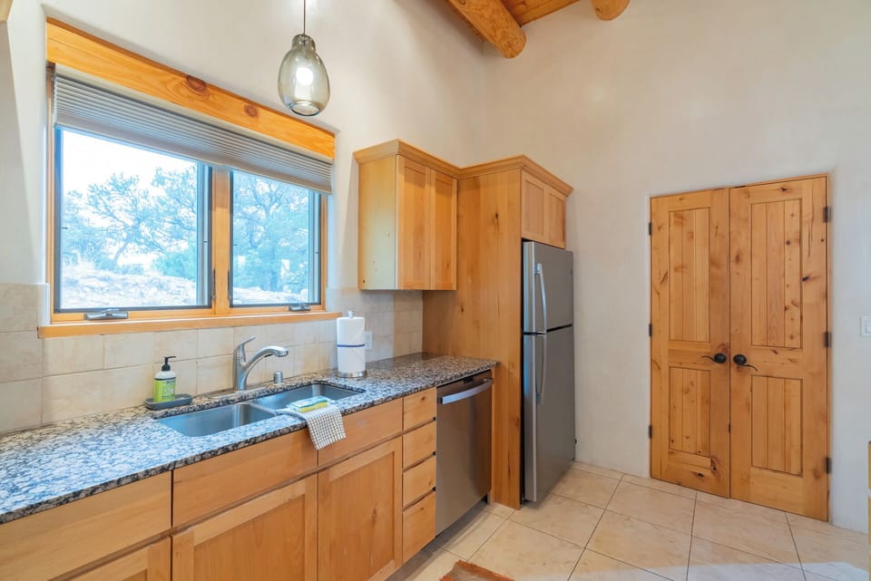 Your fully equipped kitchen features granite counters, stainless steel appliances, and natural light from a window overlooking peaceful desert views—perfect for preparing meals during your stay.