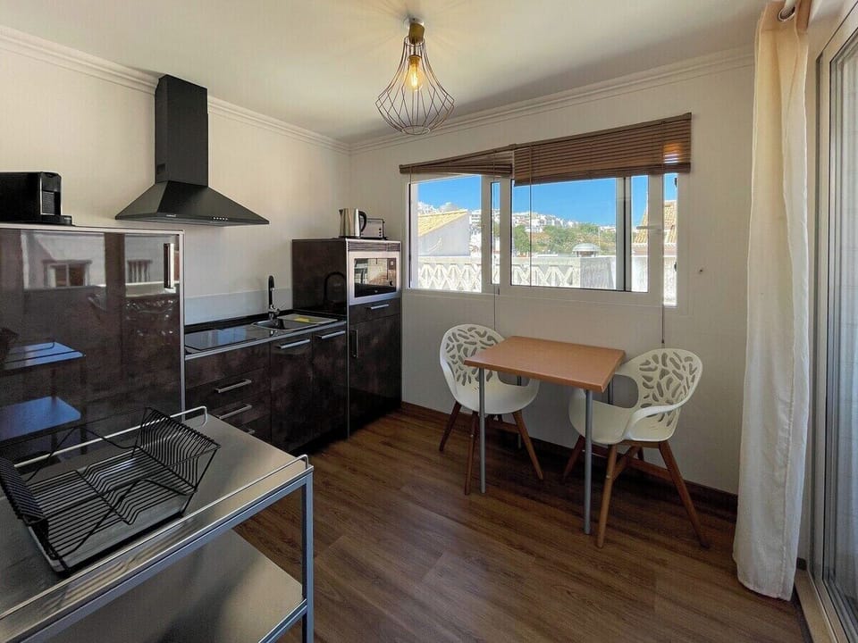 kitchen equipped with dishwasher, refrigerator, cooker, blender, kettle, microwave oven, and toaster and side table with two chairs