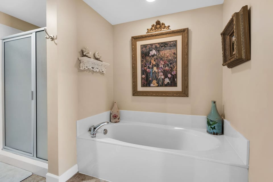 Walk-in shower, bath tub and original artwork in master bathroom. 
