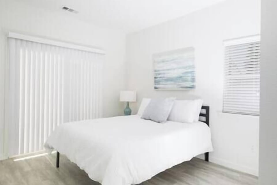 Bedroom 1 with sliding door to shared patio, offering peaceful views of olive orchard and trees.