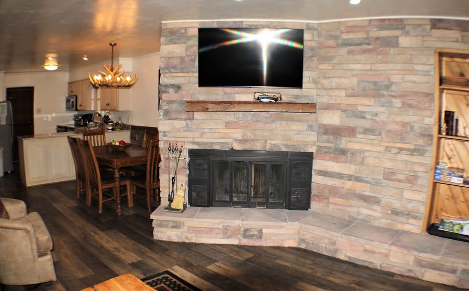 Gather around the stone fireplace while your favorite show plays on the flat-screen TV. Spacious open-concept living invites relaxation with warm wood and modern finishes throughout.