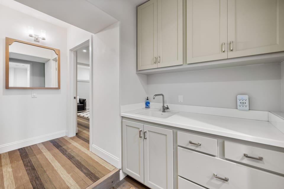 Washer and dryer area with sink and cabinets. 