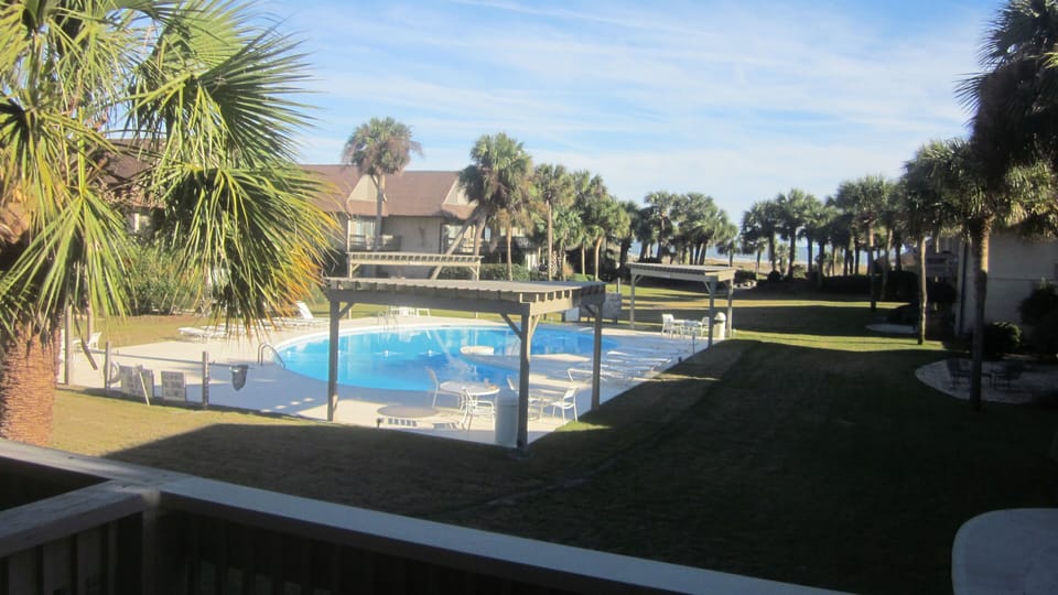 View from master bedroom balcony of pool with pergolas for shade from sun